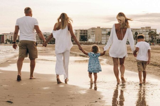 A family holding hands walks along the wet sand during a relaxing family seaside holiday by the coast.